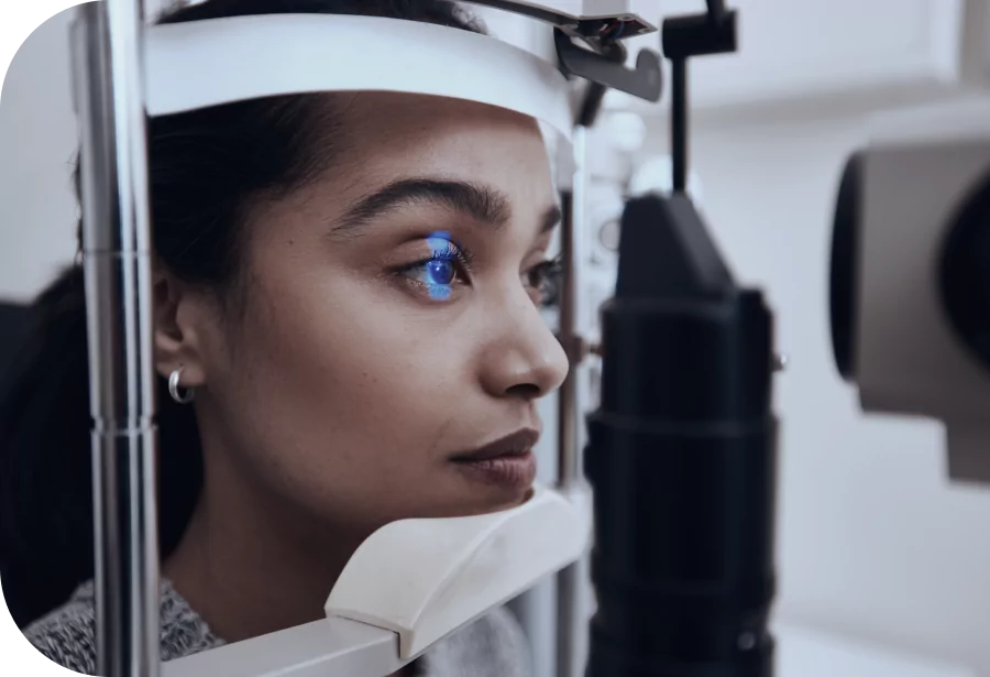 Woman resting her chin on optometry equipment having her eyes examined