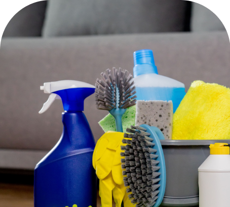 Cleaning supplies including spray bottles, sponges, and brushes in a bucket