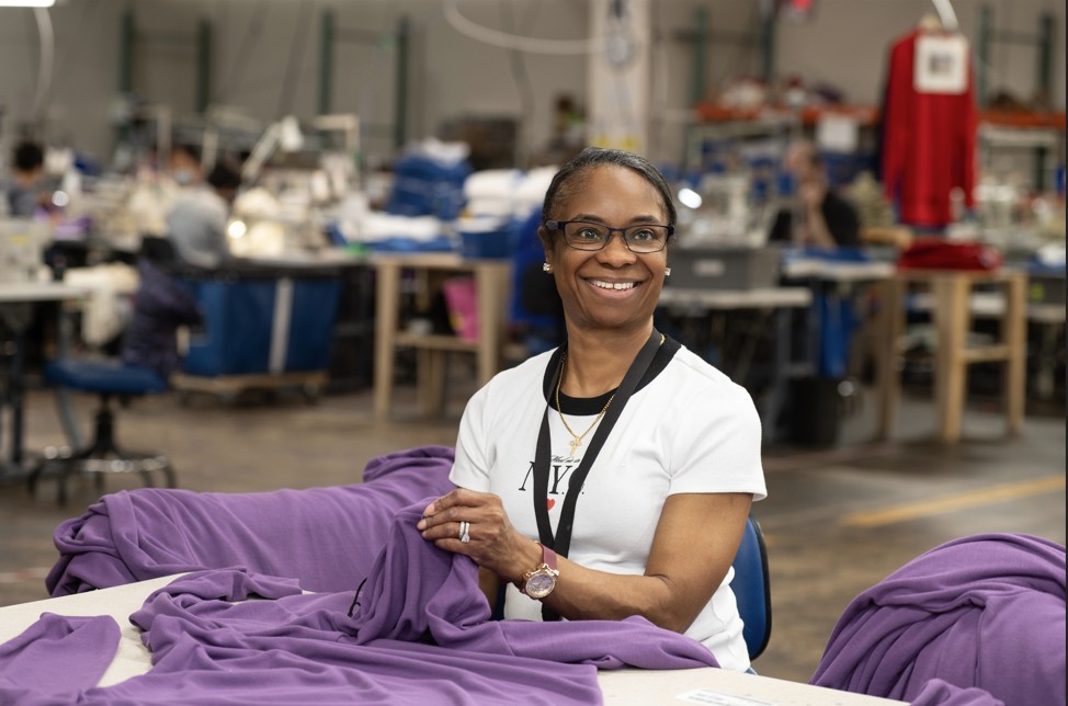 Employee Joy smiling and folding one of the Navy Flight Deck jerseys