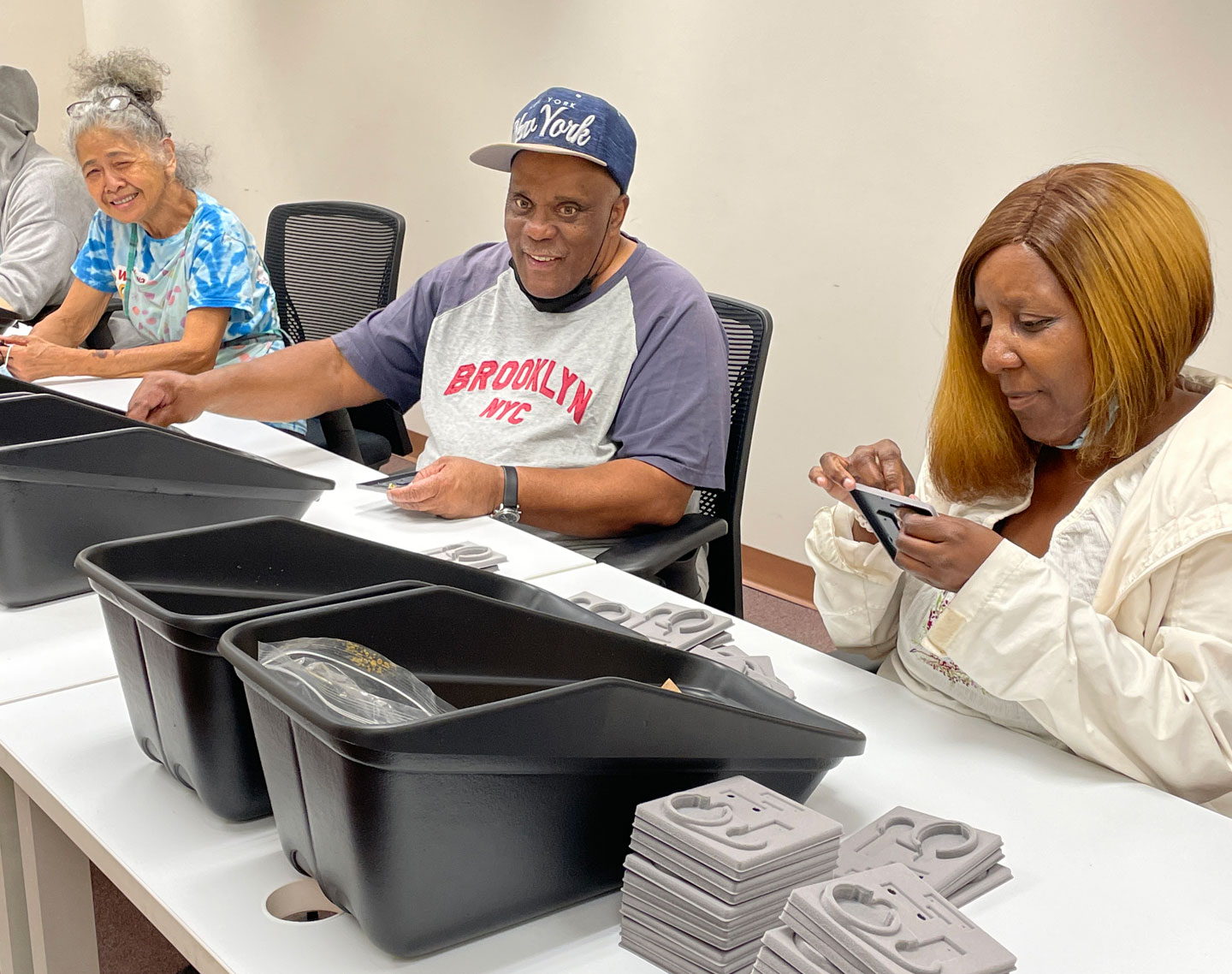 Working at Bestwork Industries for the Blind; three employees working at a table bins and gray materials