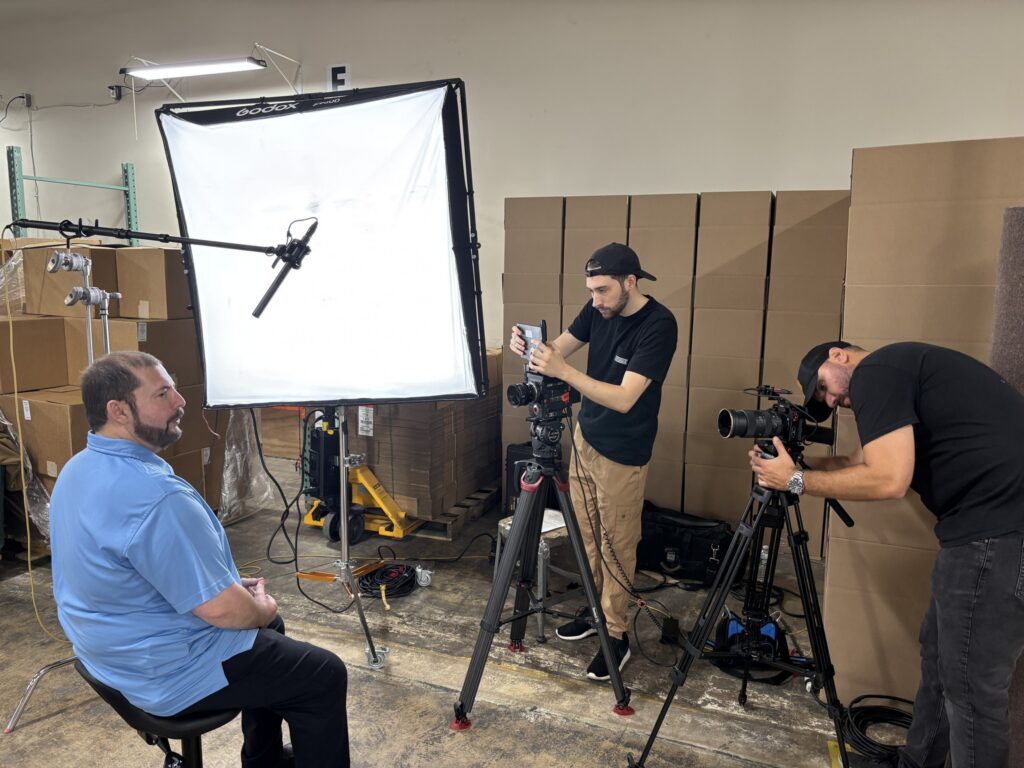 Bestwork employee Wilfredo being interviewed for a video by two gentleman with cameras